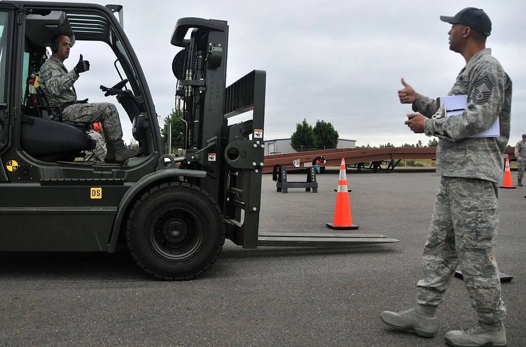 An army man is directing the forklift